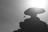 Black and white image of a mountain climber rappeling in the desert