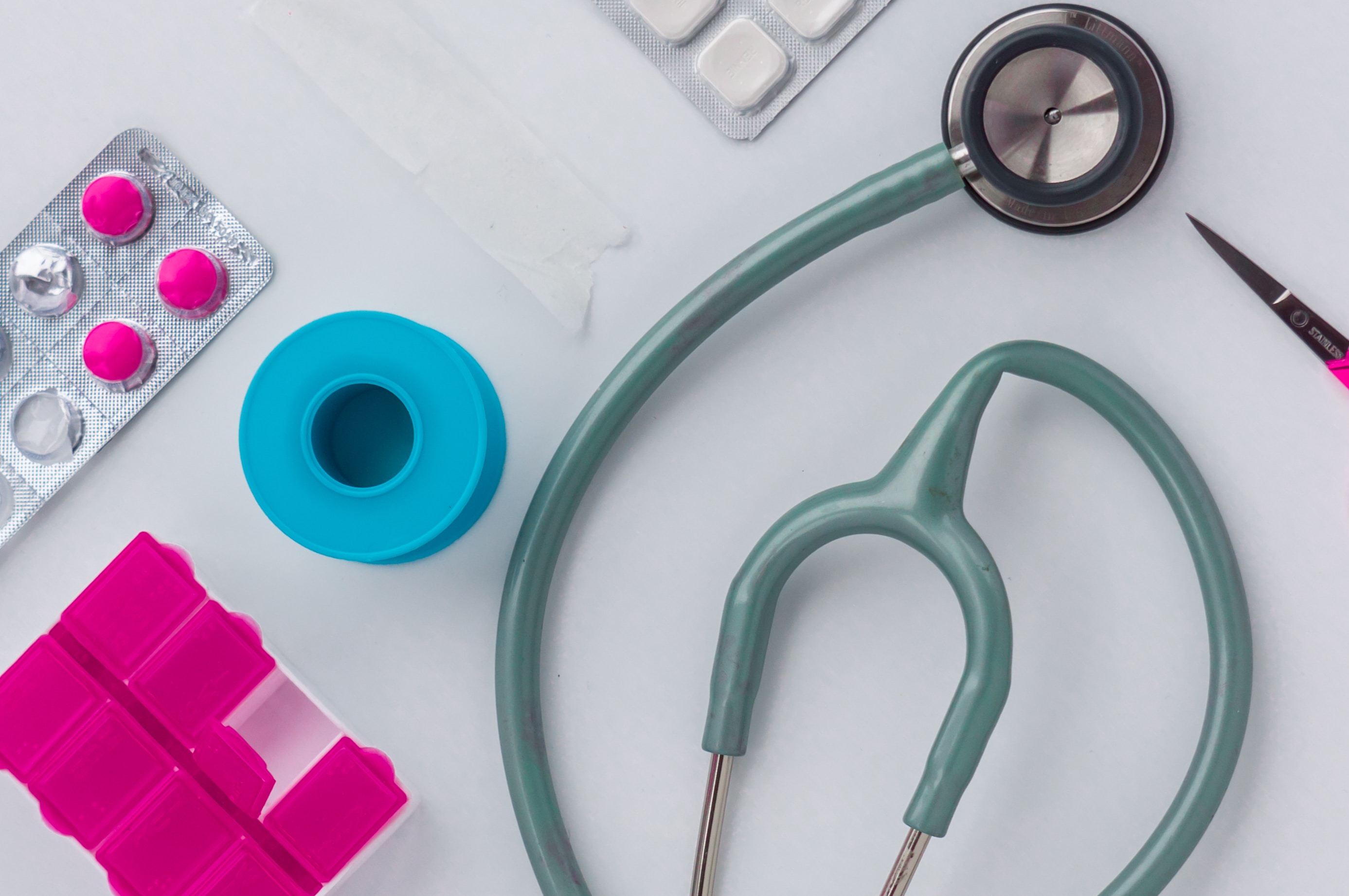 A stethoscope, medical tape, and mecicine capsule box lying on a white table